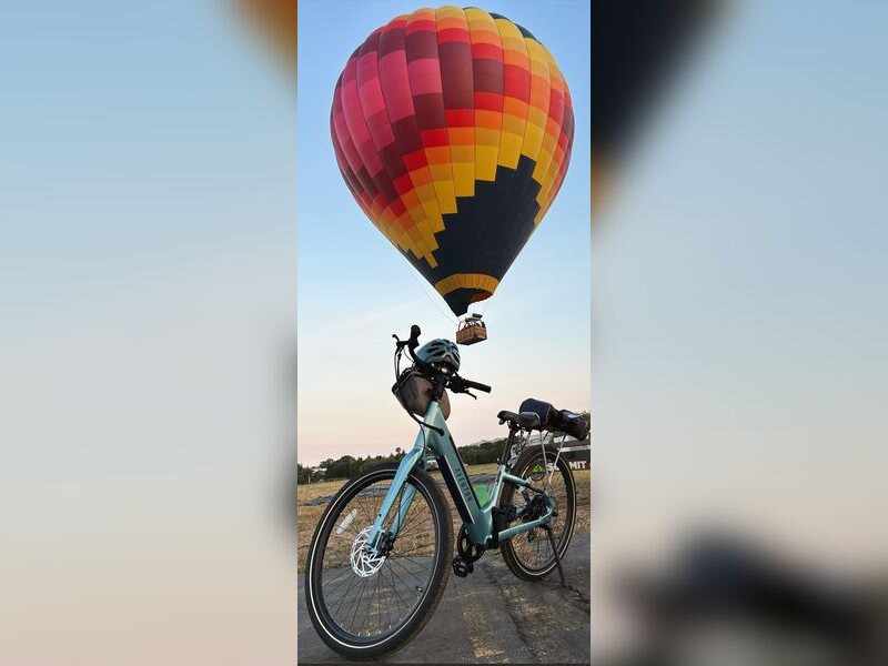 An e-bike parked below a hot air balloon overhead