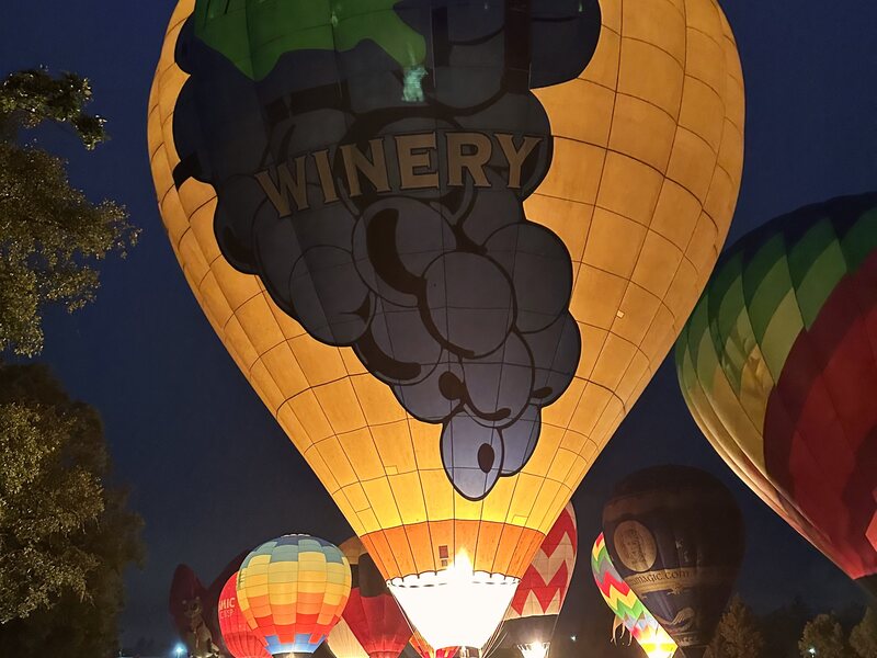Balloons glowing against the night sky at a festival event