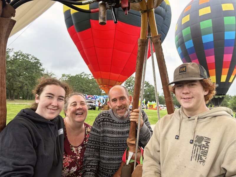 A family of four smiling beneath the balloons before flight