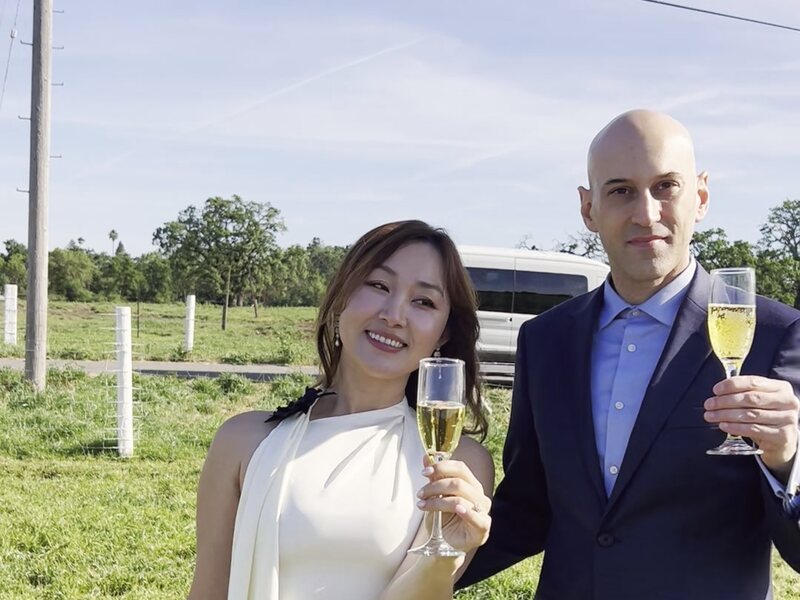 Newlyweds toasting champagne in a meadow after their balloon wedding