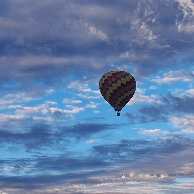 A balloon drifting through dramatic morning clouds